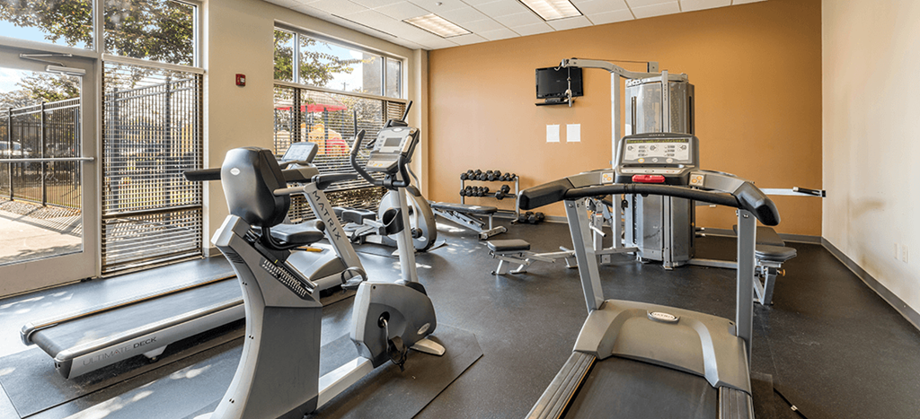 Fitness center at Quimby Plaza Apartments with cardio equipment, weights and a TV