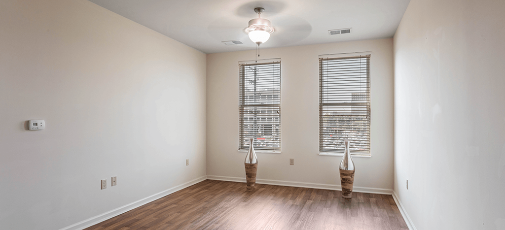 an empty living room with two windows and wood floors at Quimby Plaza Apartments