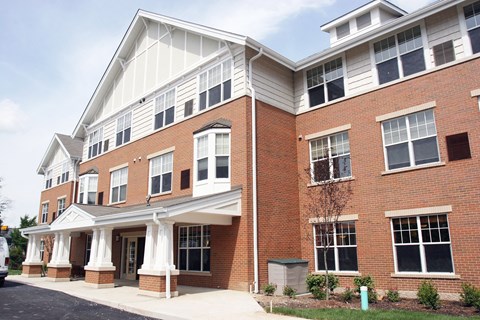 a brick apartment building with white columns and a porch