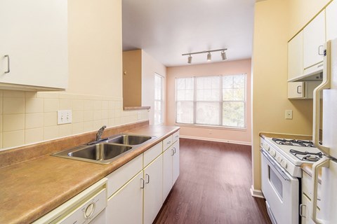 an empty kitchen with white appliances and wooden floors at Renaissance Place at Grand Apartments & Townhomes