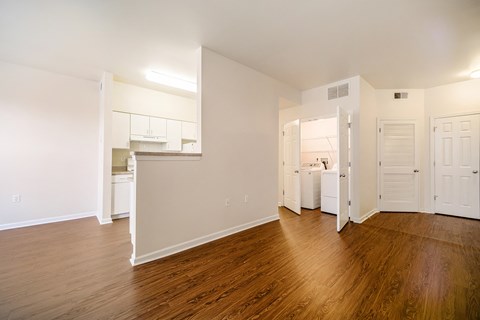 a living room and kitchen with wood flooring and white walls at Renaissance Place at Grand Apartments & Townhomes