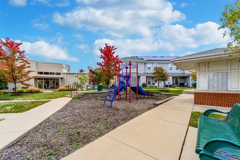 a playground in front of a building with a blue slide at Renaissance Place at Grand Apartments & Townhomes