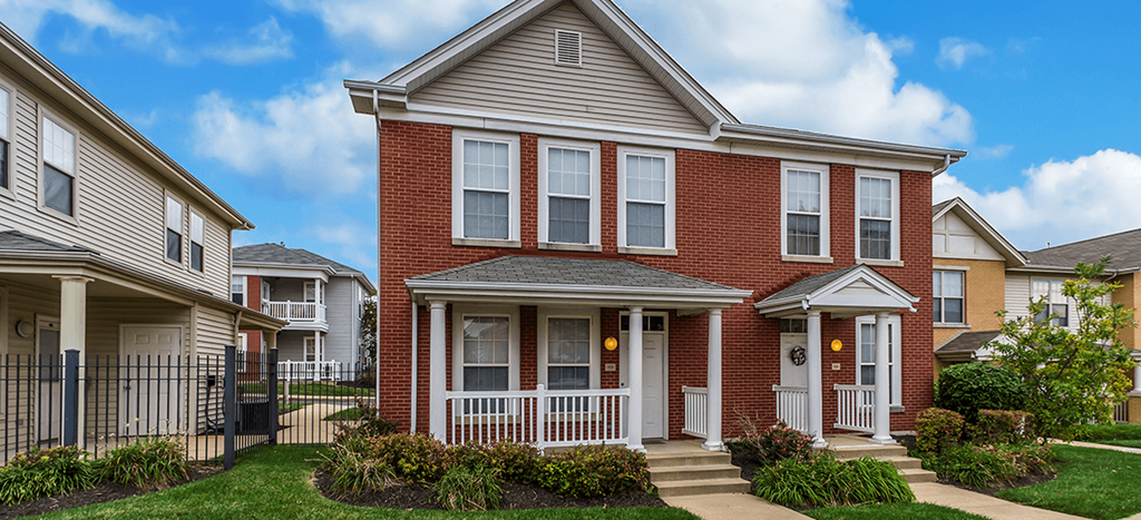 a red brick townhome with a porch and a sidewalk in front of it at Renaissance Place at Grand Apartments