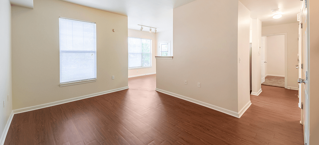 the living room and dining room of an apartment with wood flooring at Renaissance Place at Grand Apartments