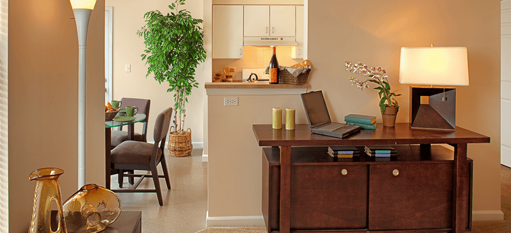 a living room and dining room with a desk with a laptop at Renaissance Place at Grand Apartments