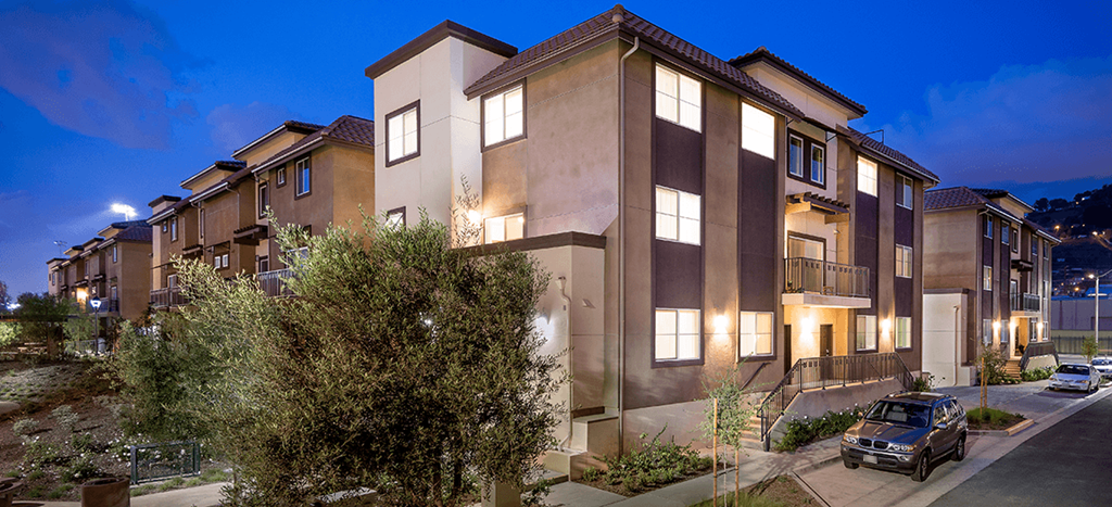 Rio Vista Apartment building at night with lush foliage and greenery along the sidewalks