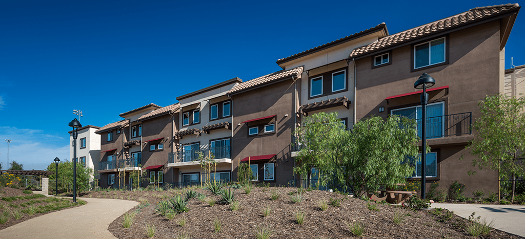 a row of apartment buildings with trees and a sidewalk at Rio Vista Apartments