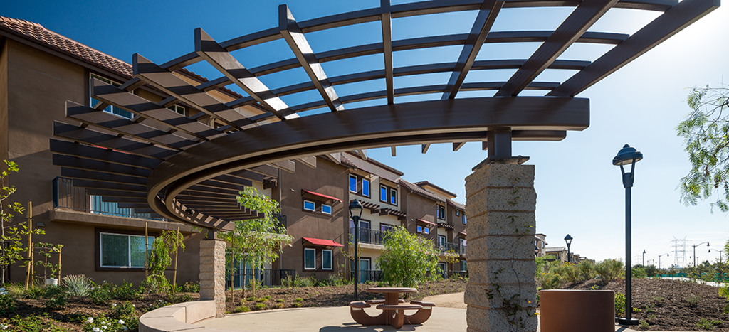 a large building with an arch over a walkway with a bench at Rio Vista Apartments