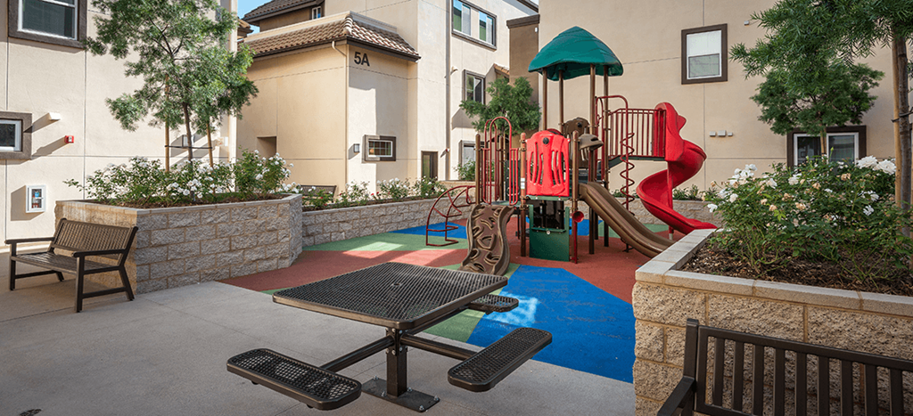 a playground at Rio Vista Apartments with a picnic table and chairs