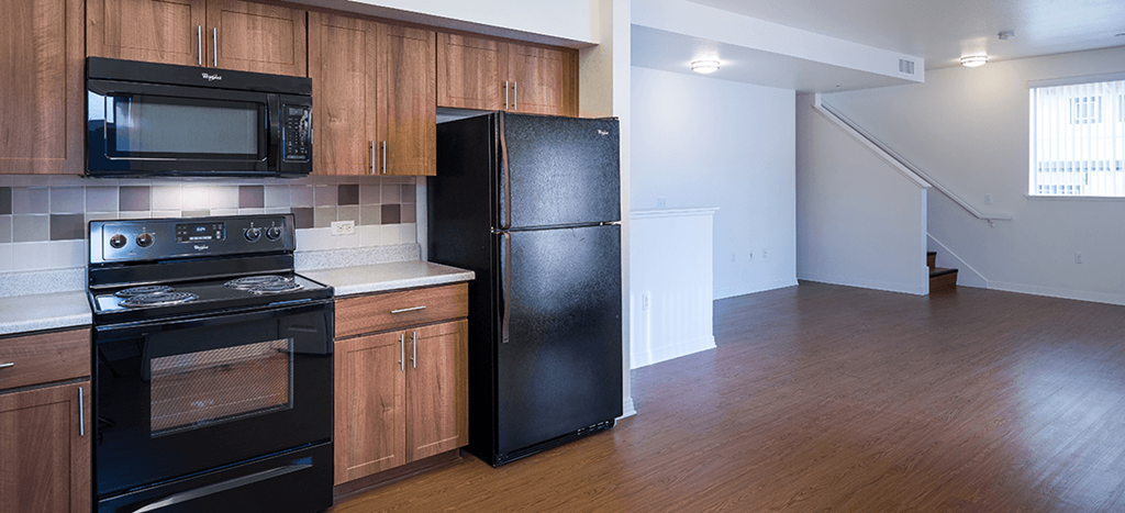 an empty kitchen with black appliances and wood flooring at Rio Vista Apartments