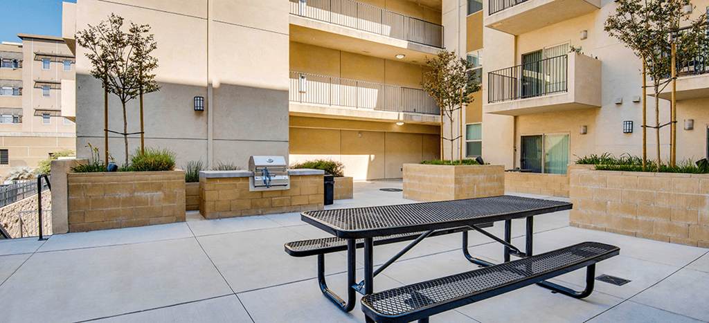 Santa Cecilia Apartments courtyard with a picnic table and a BBQ grill