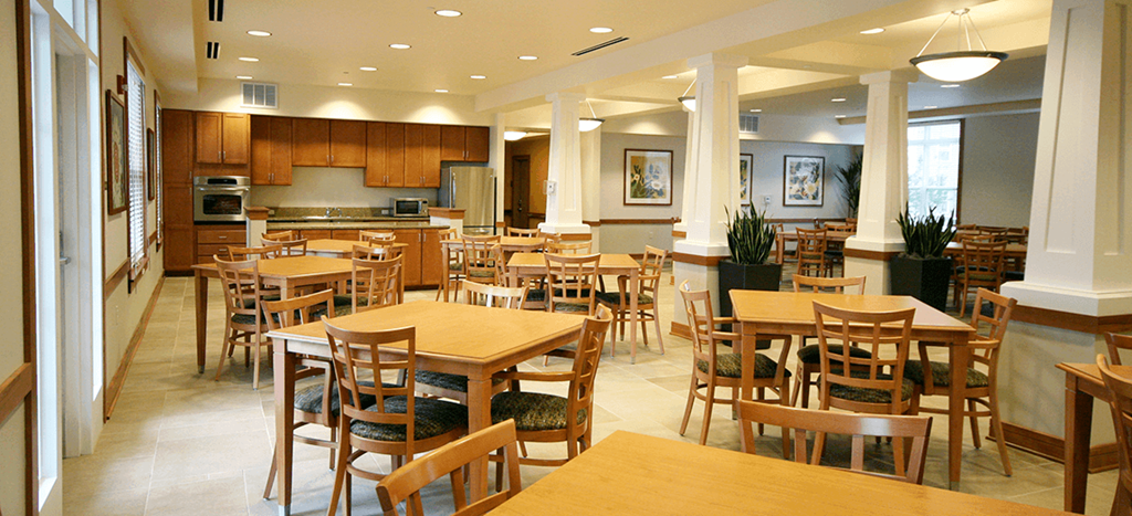 Cambridge Sr. community room with tables and chairs and a kitchen