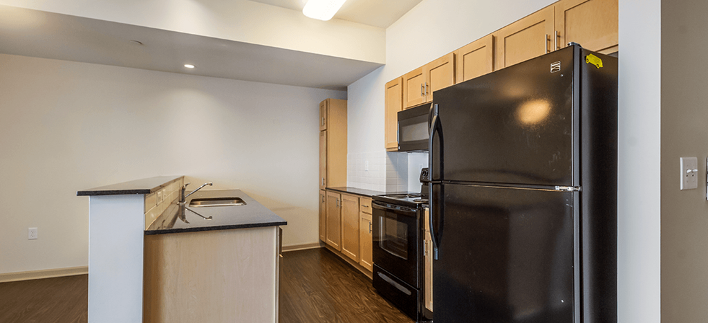 a kitchen with black appliances and a counter top and a refrigerator