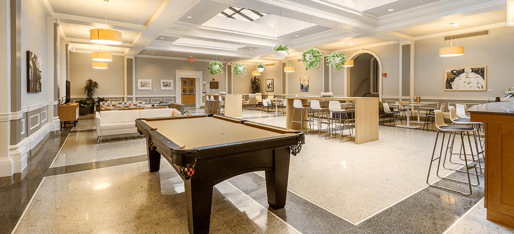 a pool table in the center of a room with tables and chairs at The Strathmore Apartments