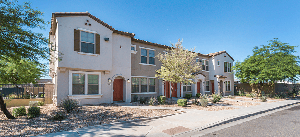 an exterior view of an apartment building with a sidewalk and trees at The Symphony