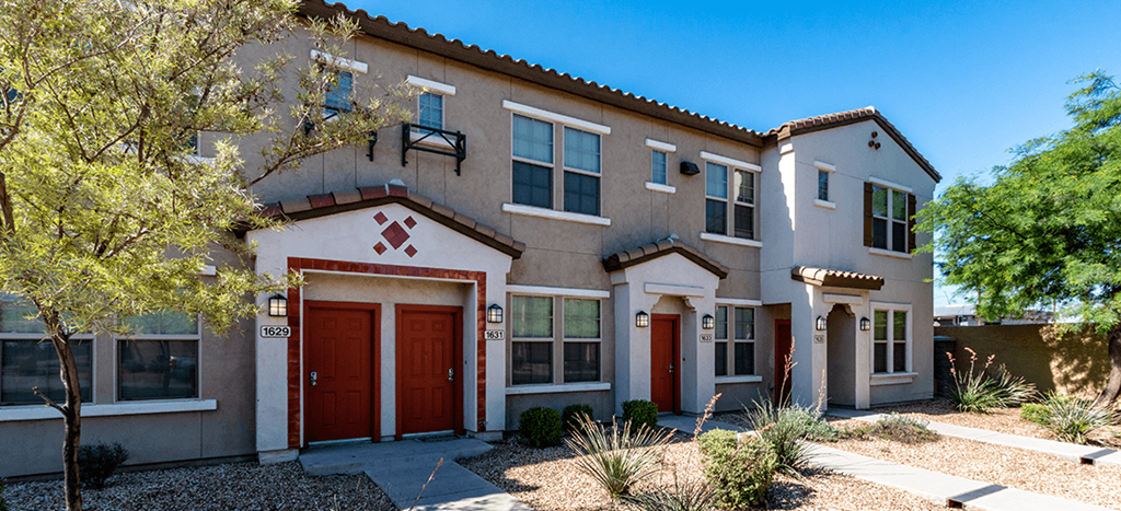 The Symphony Apartment building with multiple red doors and a sidewalk in front of it