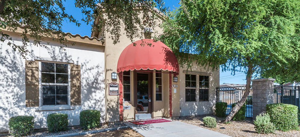 the front of the leasing office with an awning and trees at The Symphony Apartments