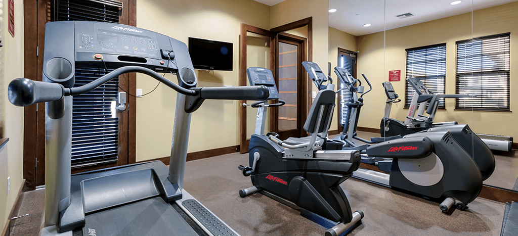 a gym with various exercise machines and a television