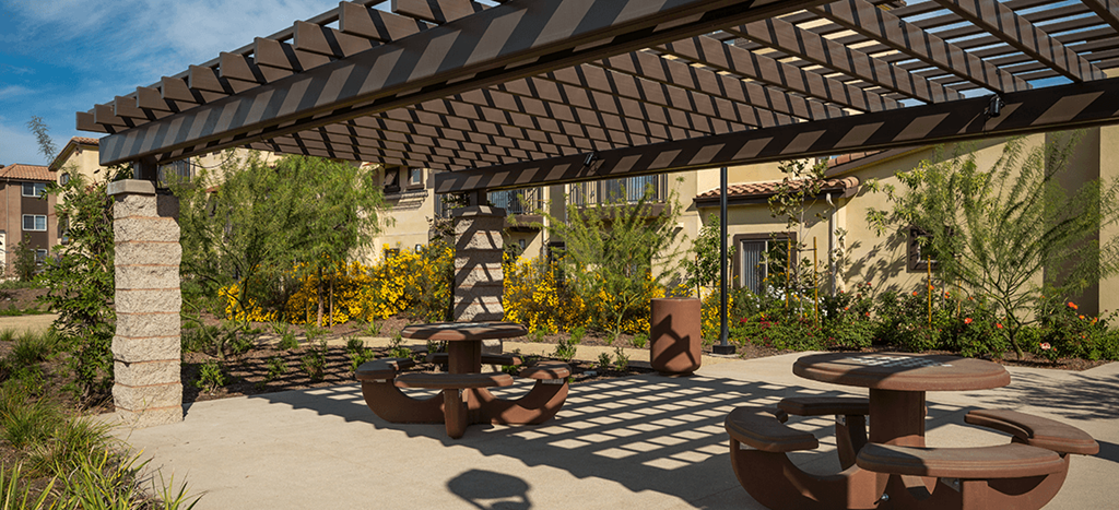 a patio with tables and a pergola at Taylor Yard Apartments