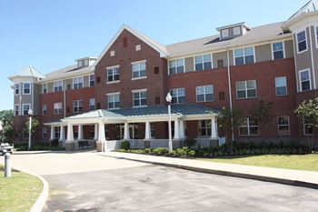 a large brick building with a porch and a driveway