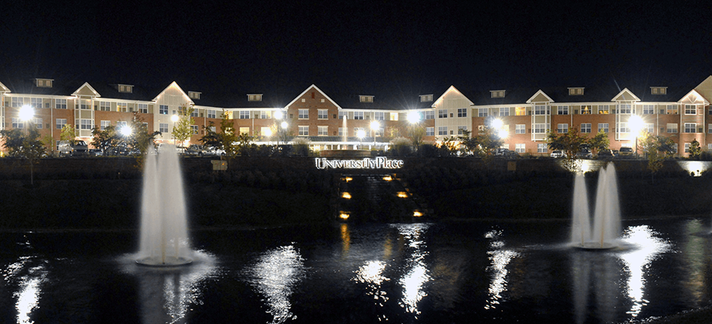 a night view of the Senior Living at University Place apartment building with water fountains