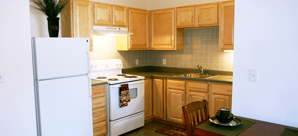 a small kitchen with white appliances and wooden cabinets at Senior Living at University Place
