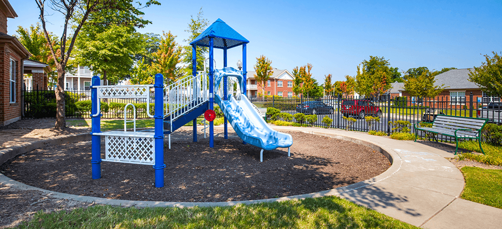 a playground with a blue slide in a park at University Place Apartments