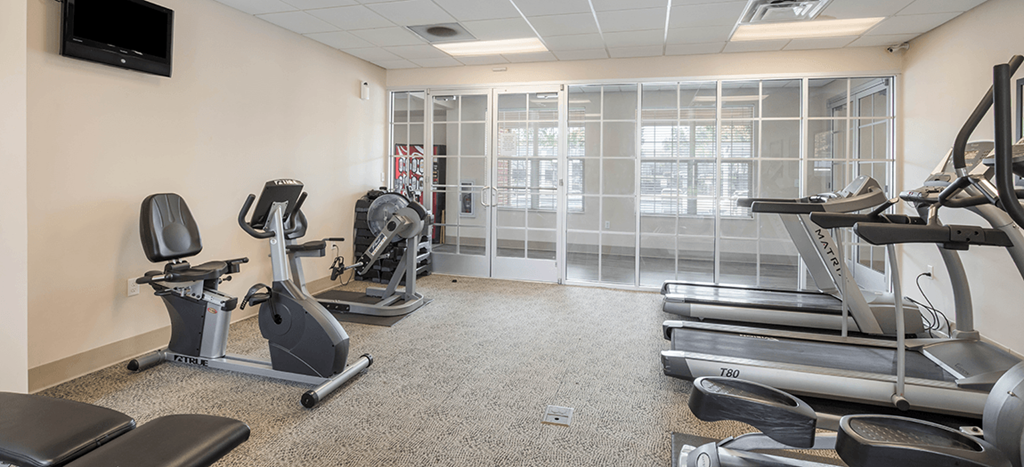 a gym with exercise equipment and a large window at University Place Apartments