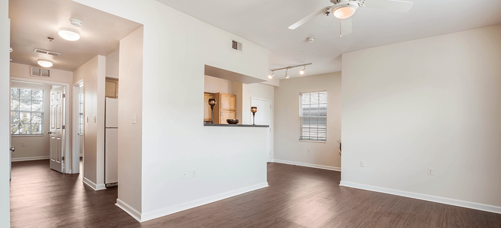 a spacious living room with white walls and wood floors at University Place Apartments