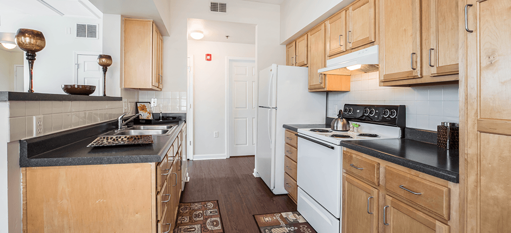 a kitchen with white appliances and wooden cabinets at University Place Apartments