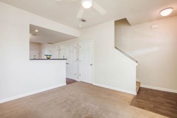 a living room and kitchen with white walls and a ceiling fan