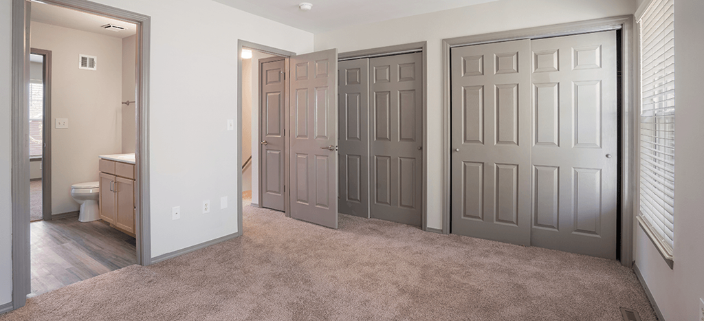 an empty bedroom with two sliding closet doors and a bathroom