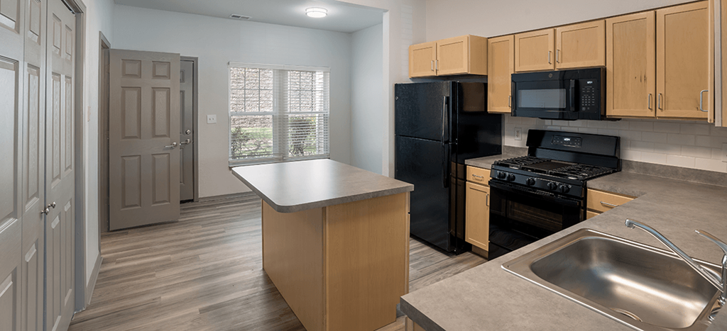 a kitchen with stainless steel appliances and wooden cabinets at Villa del Sol Apartments