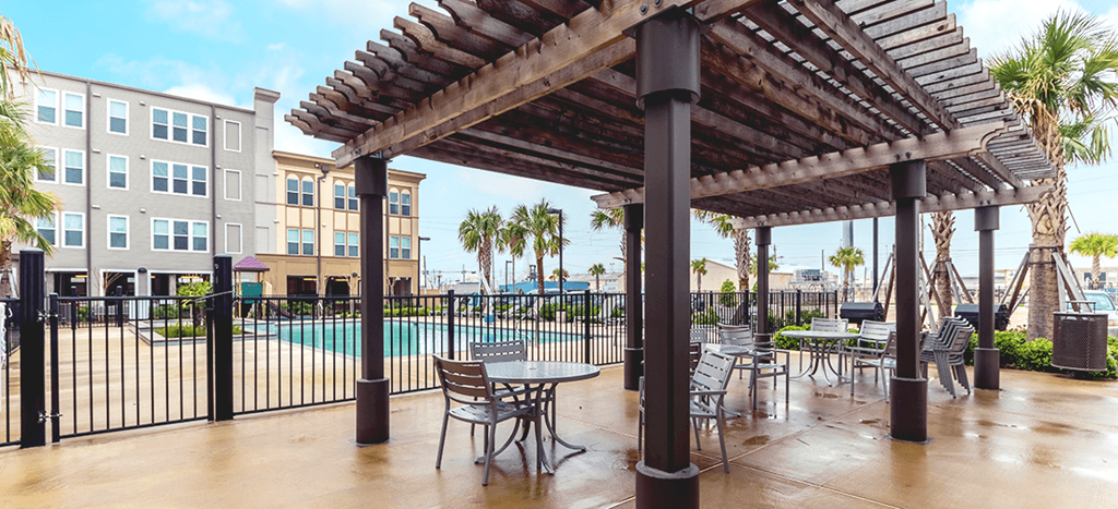 a patio with tables and chairs next to a swimming pool