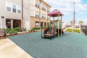 a green and red playground with stairs and a slide at Villas on the Strand apartments in Galveston, TX