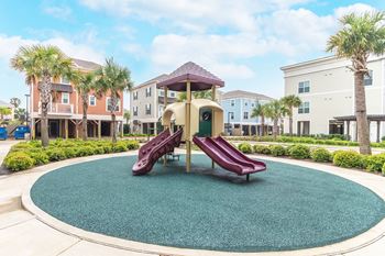 a green and red playground with stairs and a slide at Villas on the Strand apartments in Galveston, TX