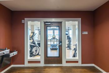 a fitness room with glass doors and gym equipment at Villas on the Strand apartments in Galveston, TX