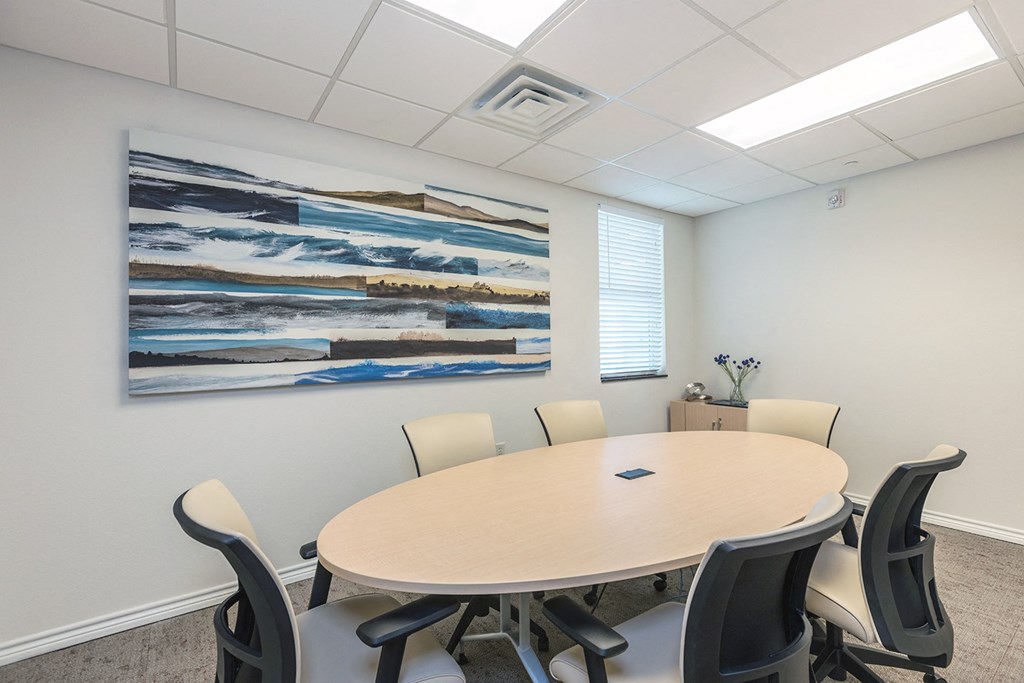a conference room with a round table and a painting on the wall