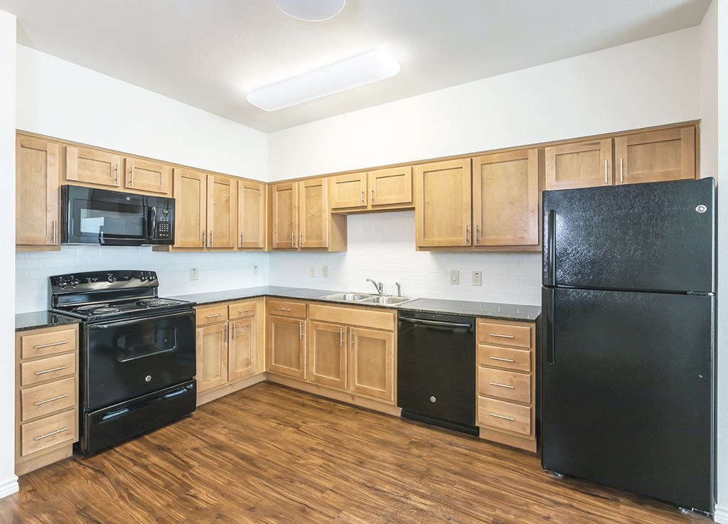 an empty kitchen with black appliances and wooden cabinets