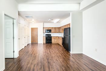 an empty kitchen with wood flooring and a black refrigerator at Villas on the Strand apartments in Galveston, TX
