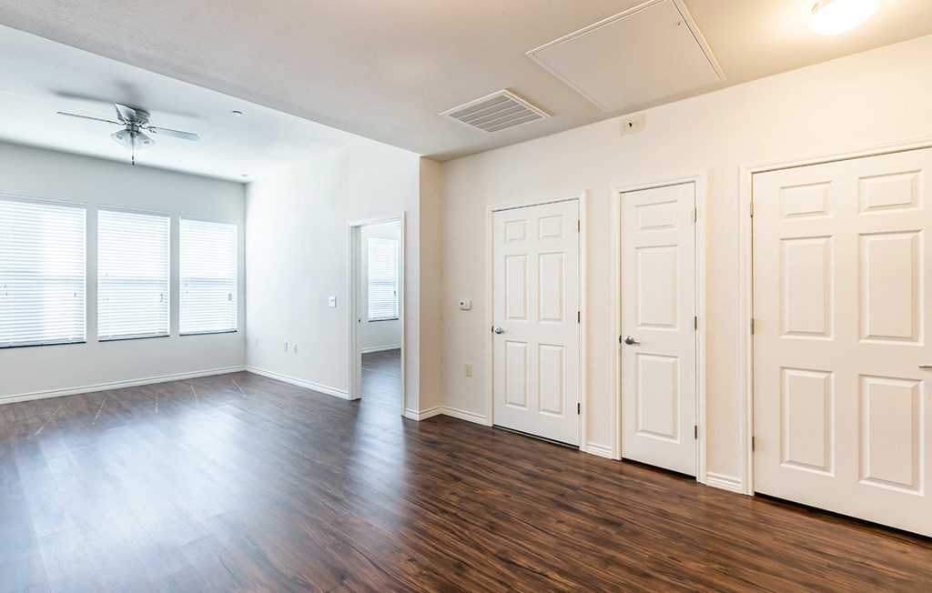 an empty living room with wood floors and white doors