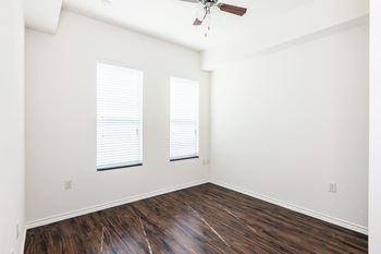 a bedroom with white walls and wood floors and a ceiling fan
