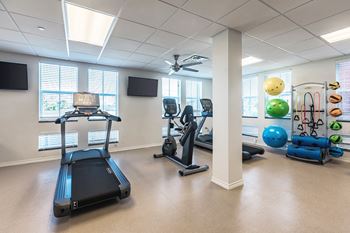 a gym with various machines and weights and a television at Villas on the Strand apartments in Galveston, TX