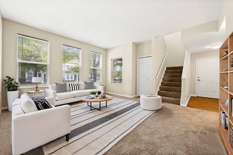 A living room with a white couch and a striped rug.