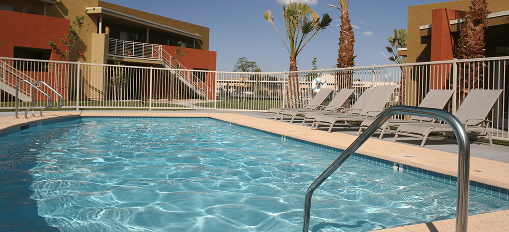 a swimming pool at Vista Sunrise Apartments with chairs and a fence
