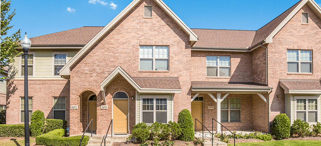 a large brick townhouse with stairs in front of it at West Park Apartments