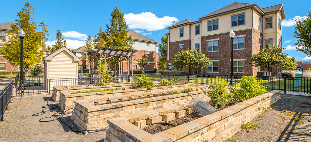 a community garden in front of a row of apartment buildings at West Park Apartments