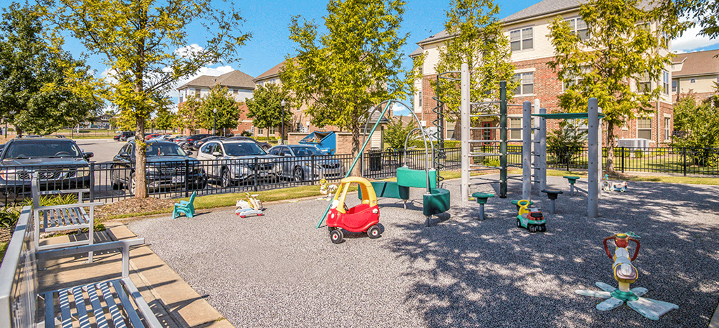 a childrens playground with toys in front of a building at West Park Apartments