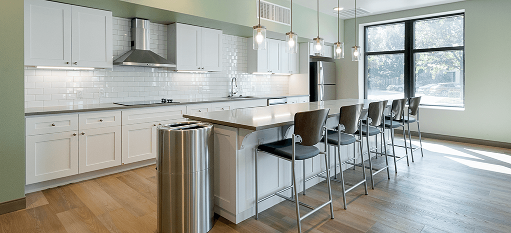 a large kitchen with white cabinets and a bar with stools at the clubhouse at West Park Apartments