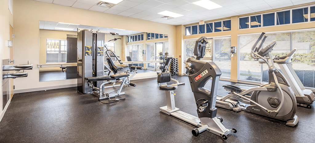 a gym with various exercise machines and windows at West Park Apartments